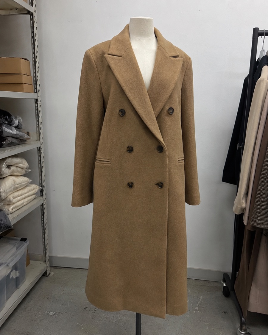 The same overcoat on a dress form in a stockroom, photographed on a phone
